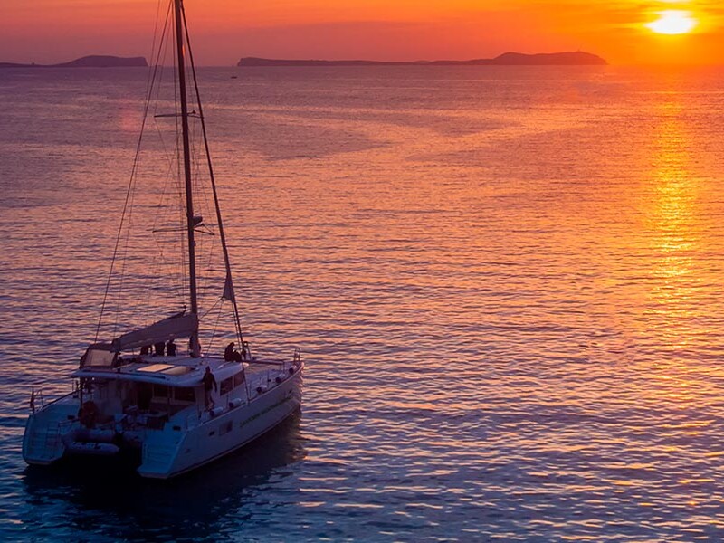 Catamaran sailing in the Santorini sunset with bright red sky